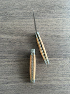 Two views of the olive wood knife on a pale wood surface