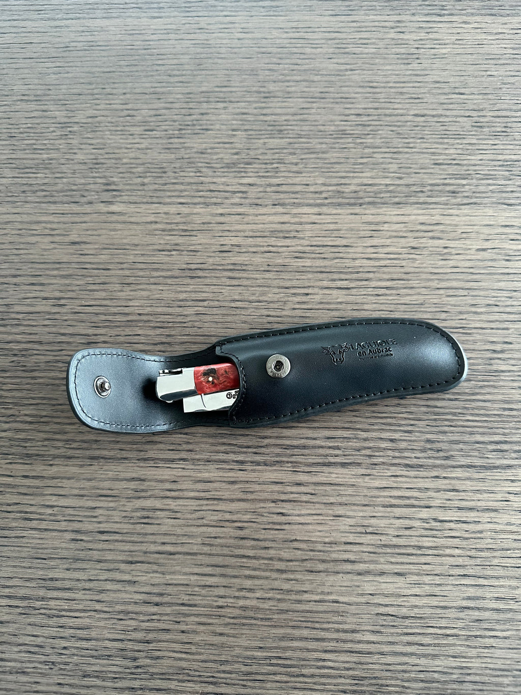 Black sheath opened with the snap and a knife tucked inside
