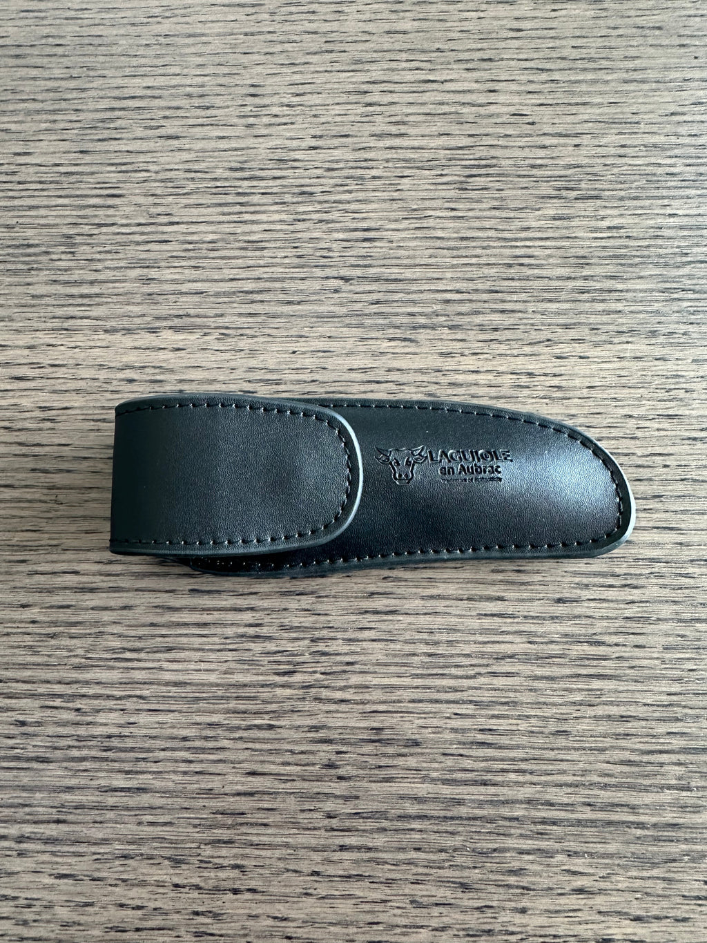 Closed black leather sheath on a dark wood surface