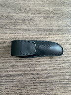 Closed black leather sheath on a dark wood surface