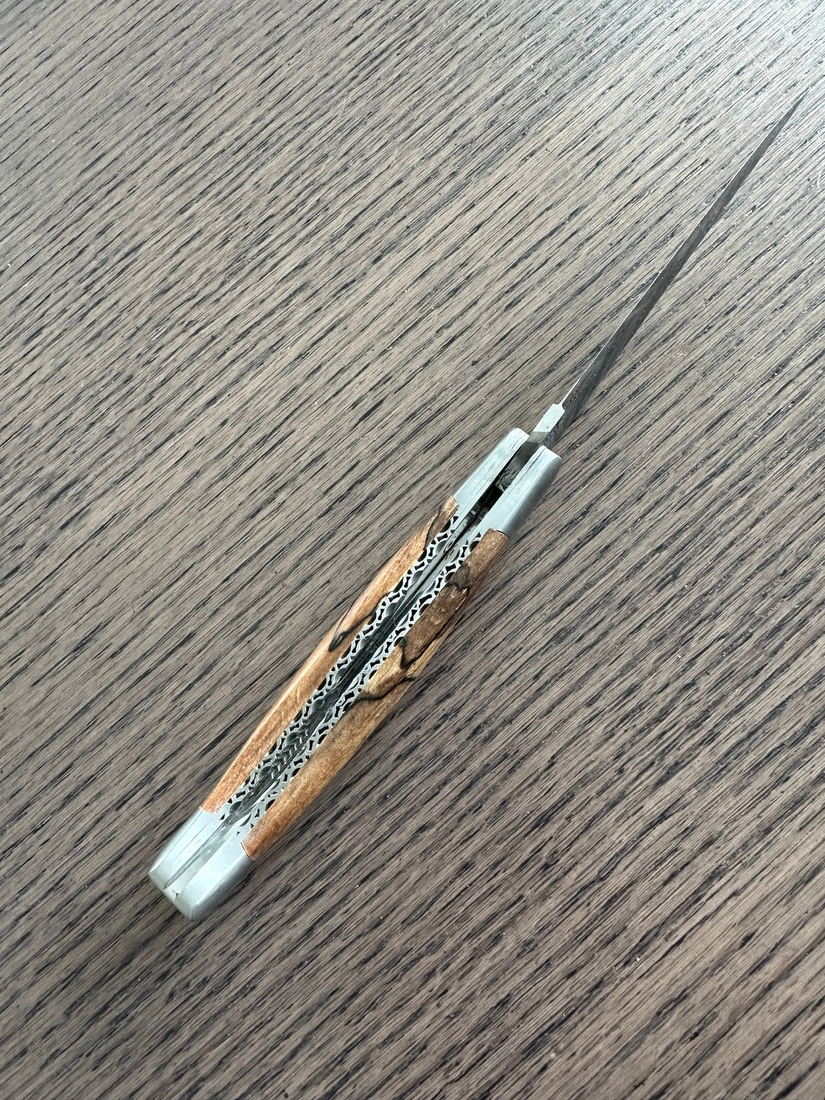 Open knife lying diagonally on a dark wood table