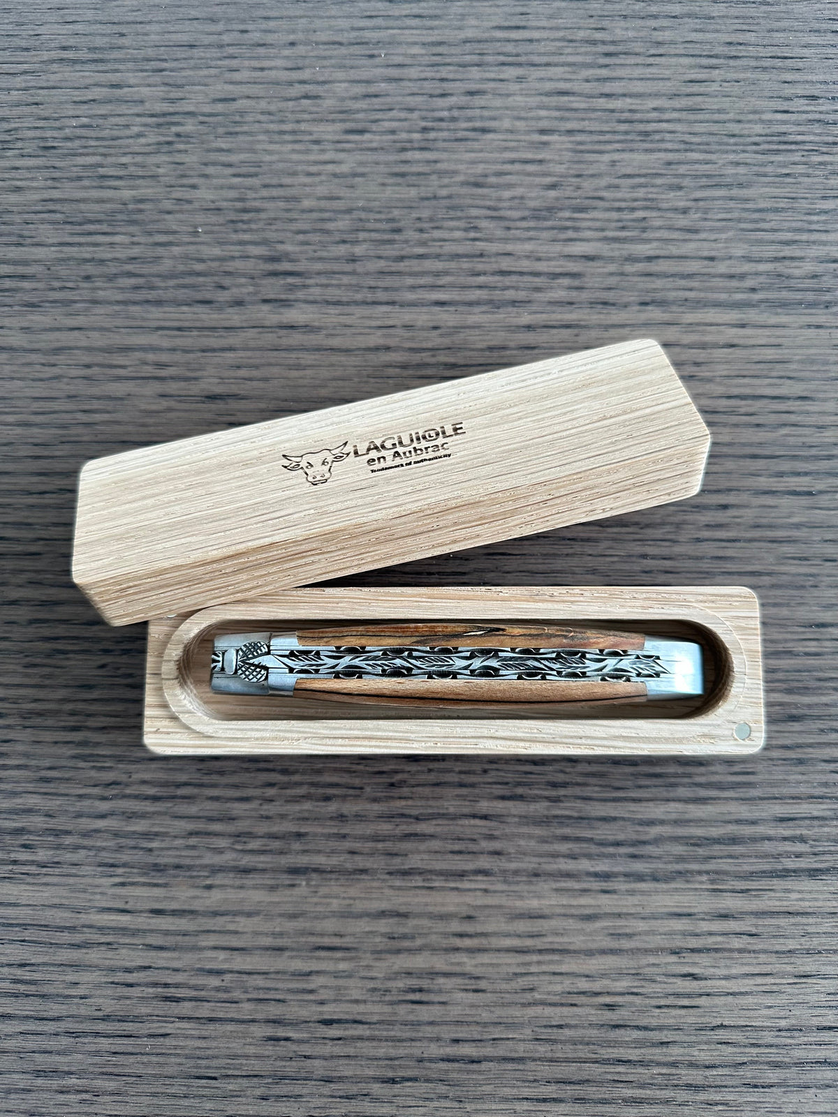 Closed knife in its open wooden storage box