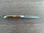 Open knife seen from the side on a wood table