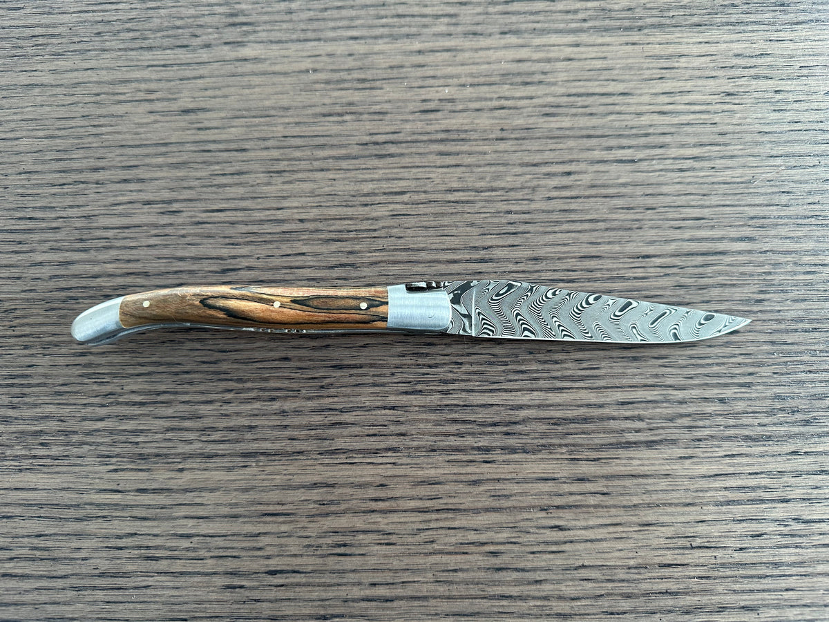 Open knife seen from the side on a wood table