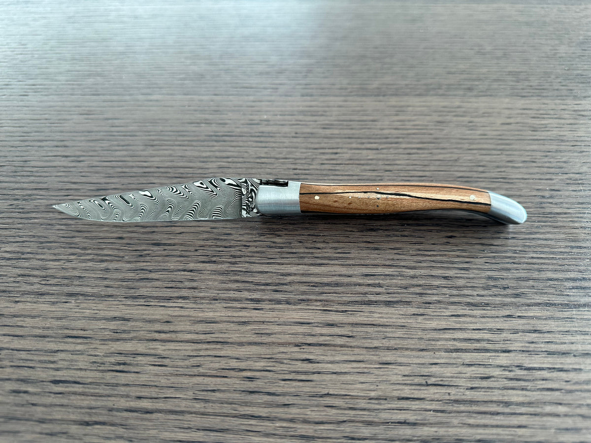 Open Damascus knife with the blade pointing left