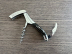 Opened corkscrew with the lever and spiral out on a wood table