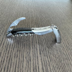 Corkscrew standing opened on the table with the foil cutter raised