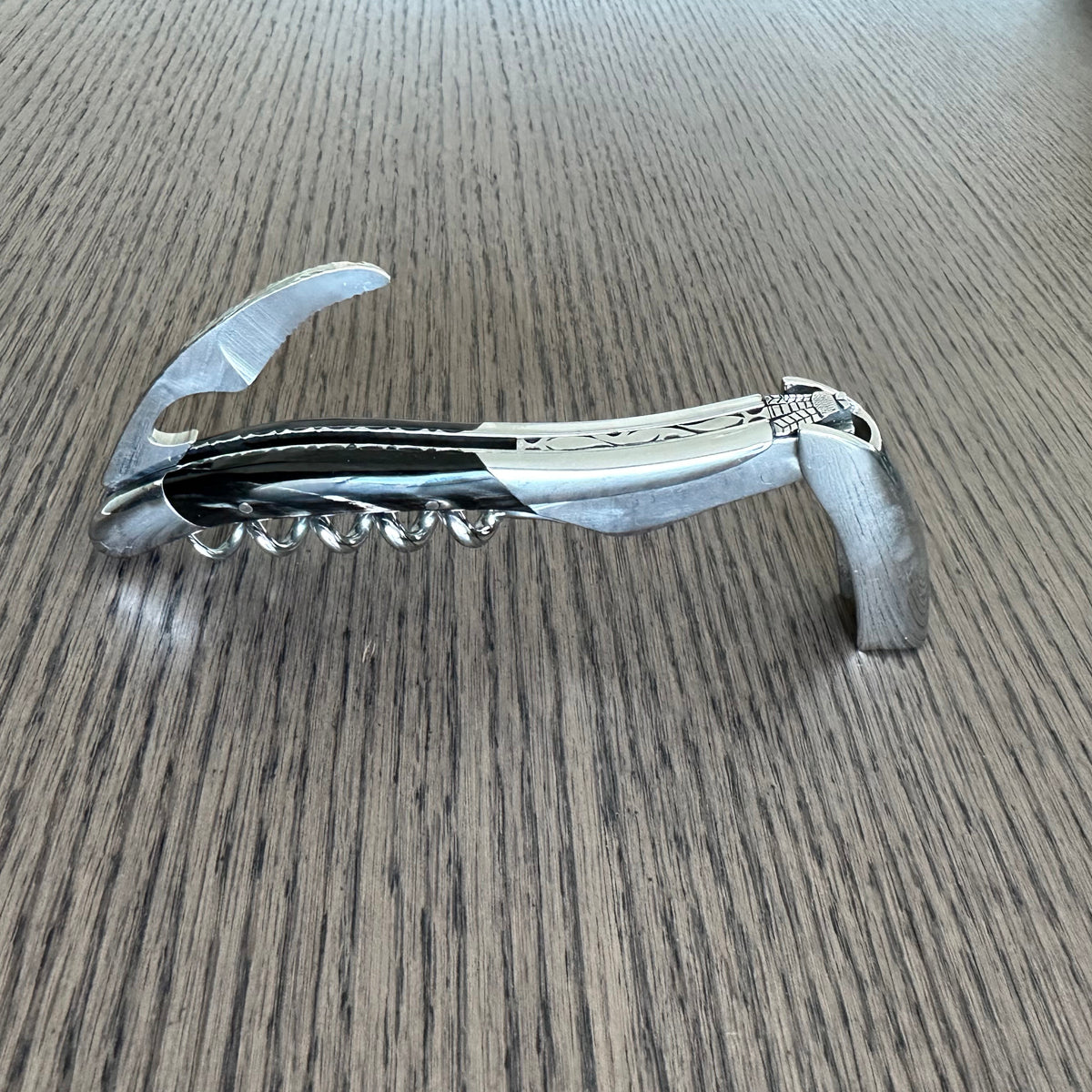 Corkscrew standing opened on the table with the foil cutter raised