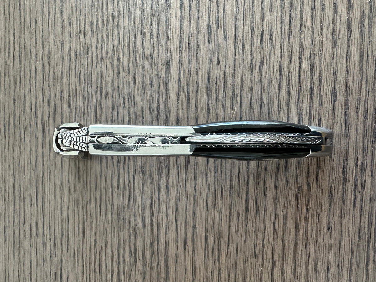 Folded corkscrew lying on a wood table, spine facing up