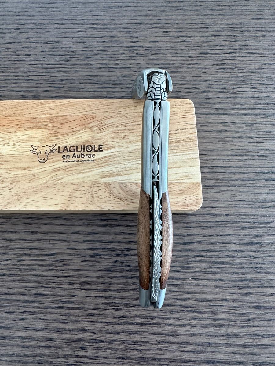 Folded corkscrew standing against the engraved oak box