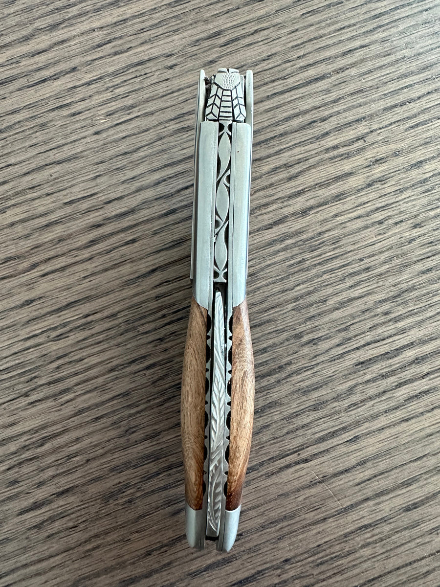 Folded corkscrew standing upright on a wood table, spine facing up