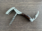 Opened corkscrew showing the foil cutter, spiral and lever on a wood table