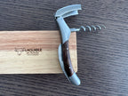 Corkscrew standing with lever and spiral open against the oak box lid