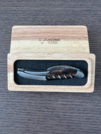 Corkscrew in the open box on a dark wood table