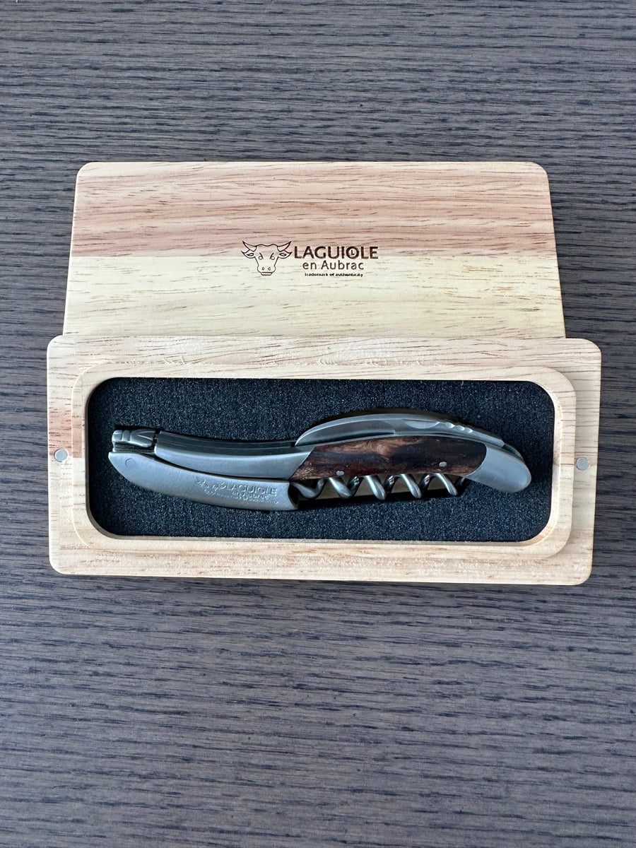 Corkscrew in the open box on a dark wood table