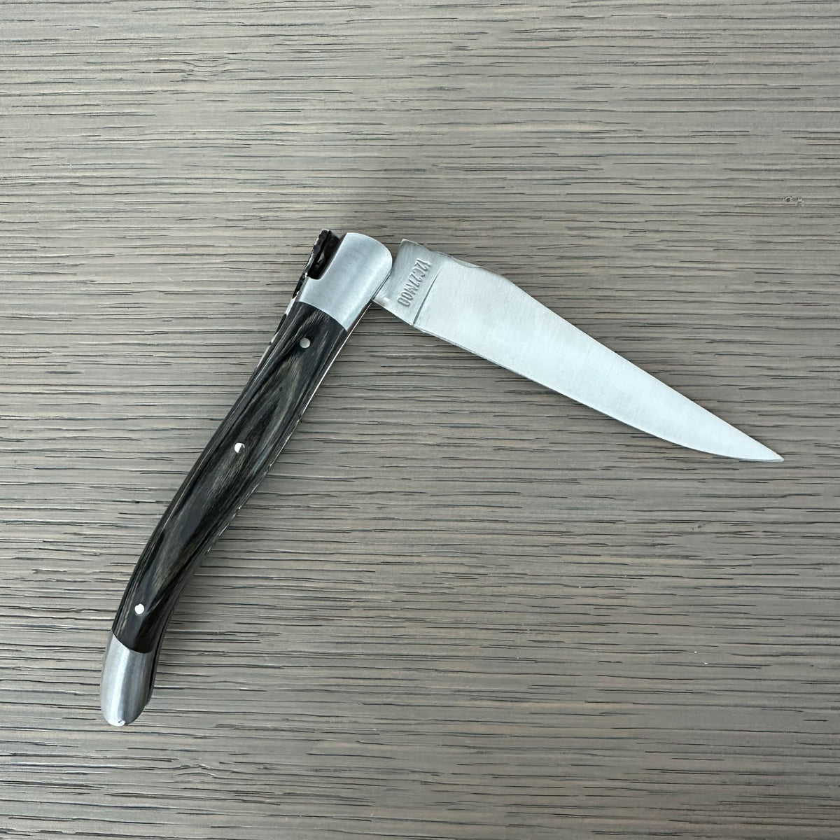 Grey pakka knife half open with the blade pointing right