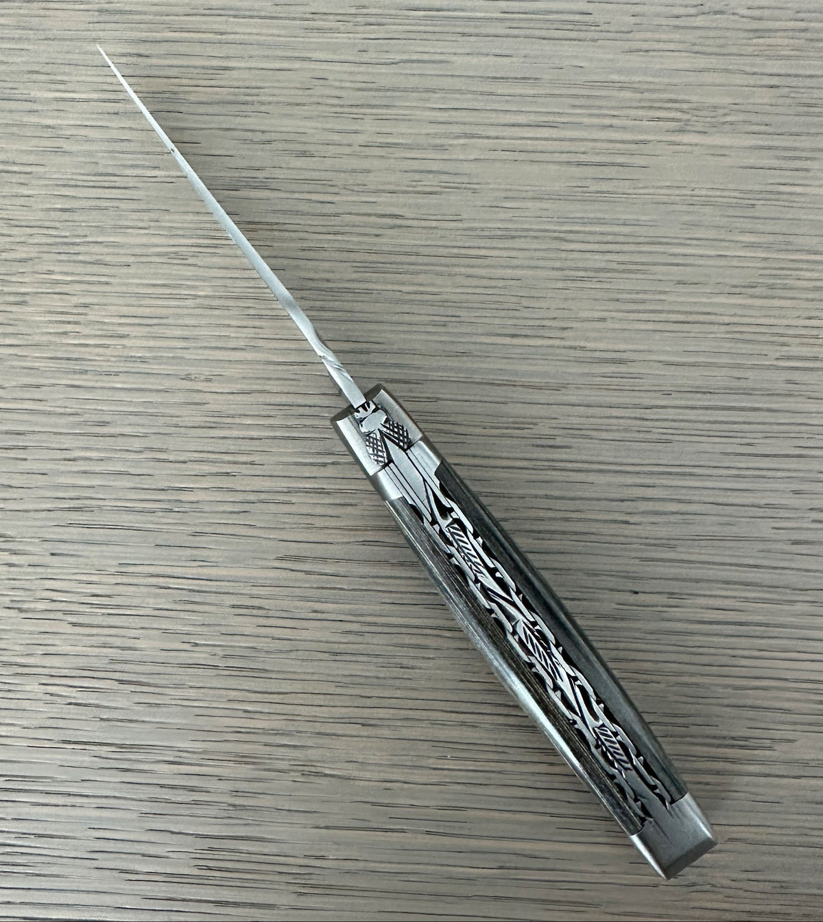 Open grey pakka knife lying diagonally, showing the filed plates