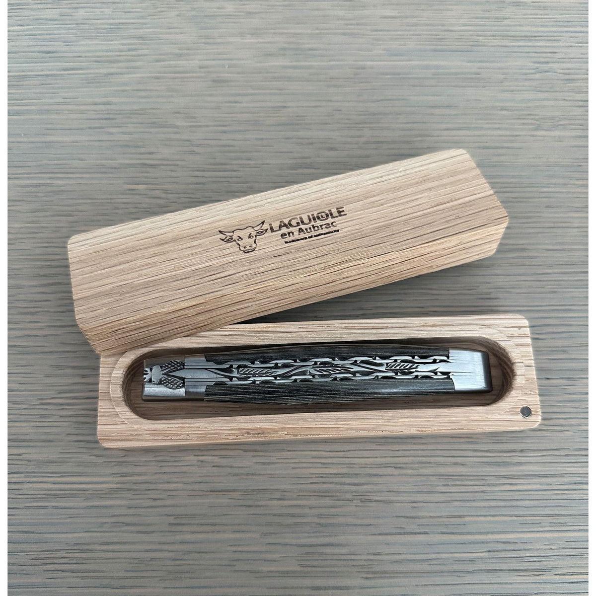Closed knife resting in its open wooden storage box