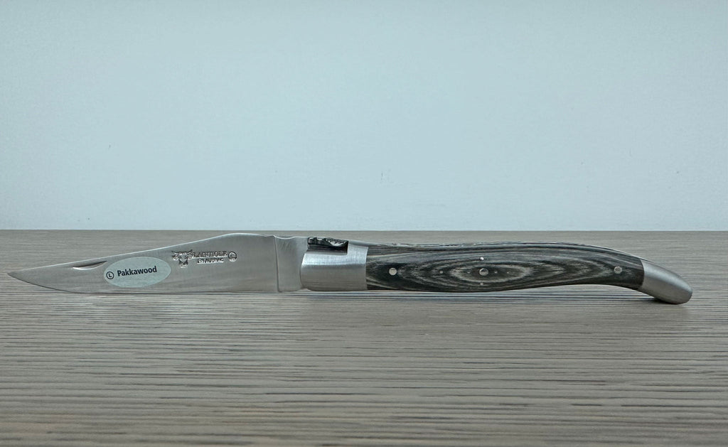 Open knife seen from the side against a pale wall