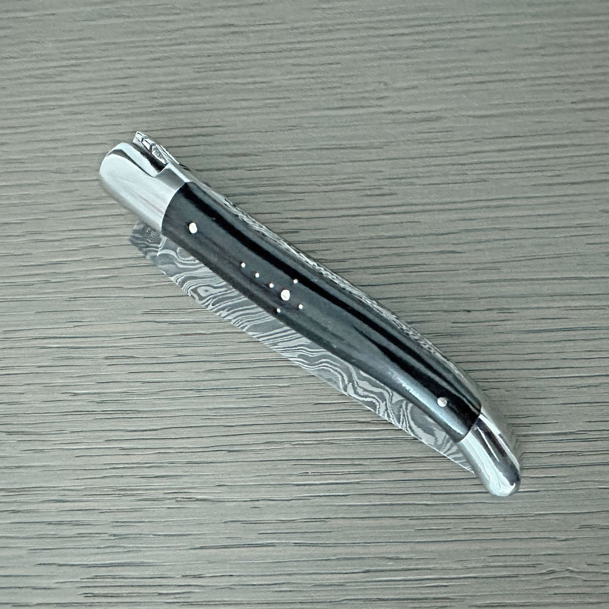 Knife with the Damascus blade folded, horn handle facing up