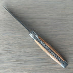 Open knife lying diagonally showing the olive wood and filed plates