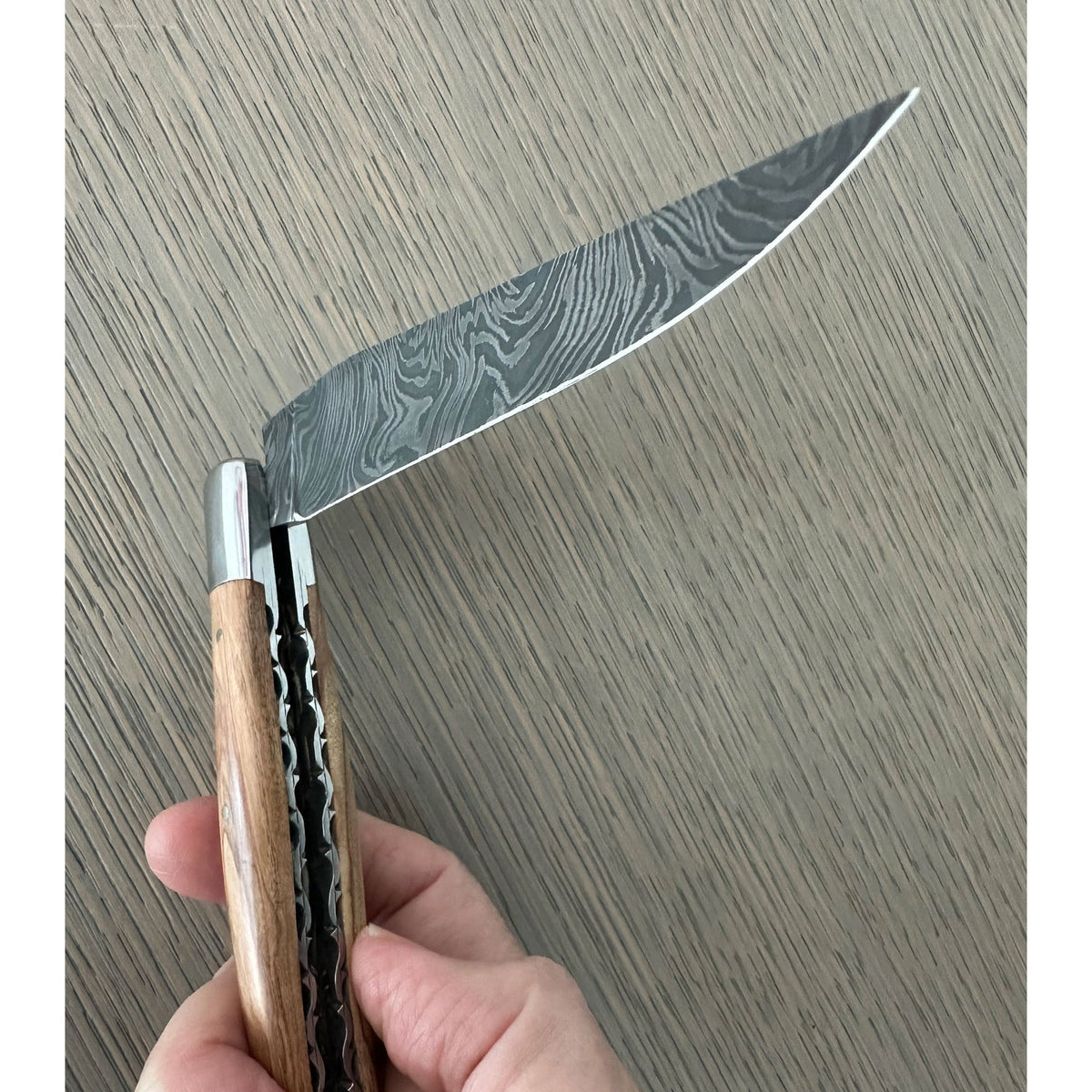 Hand holding the knife to show the Damascus blade pattern