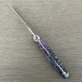 Laguiole Cosmos Saturn purple knife with indigo elder burl handle, open on pale wood