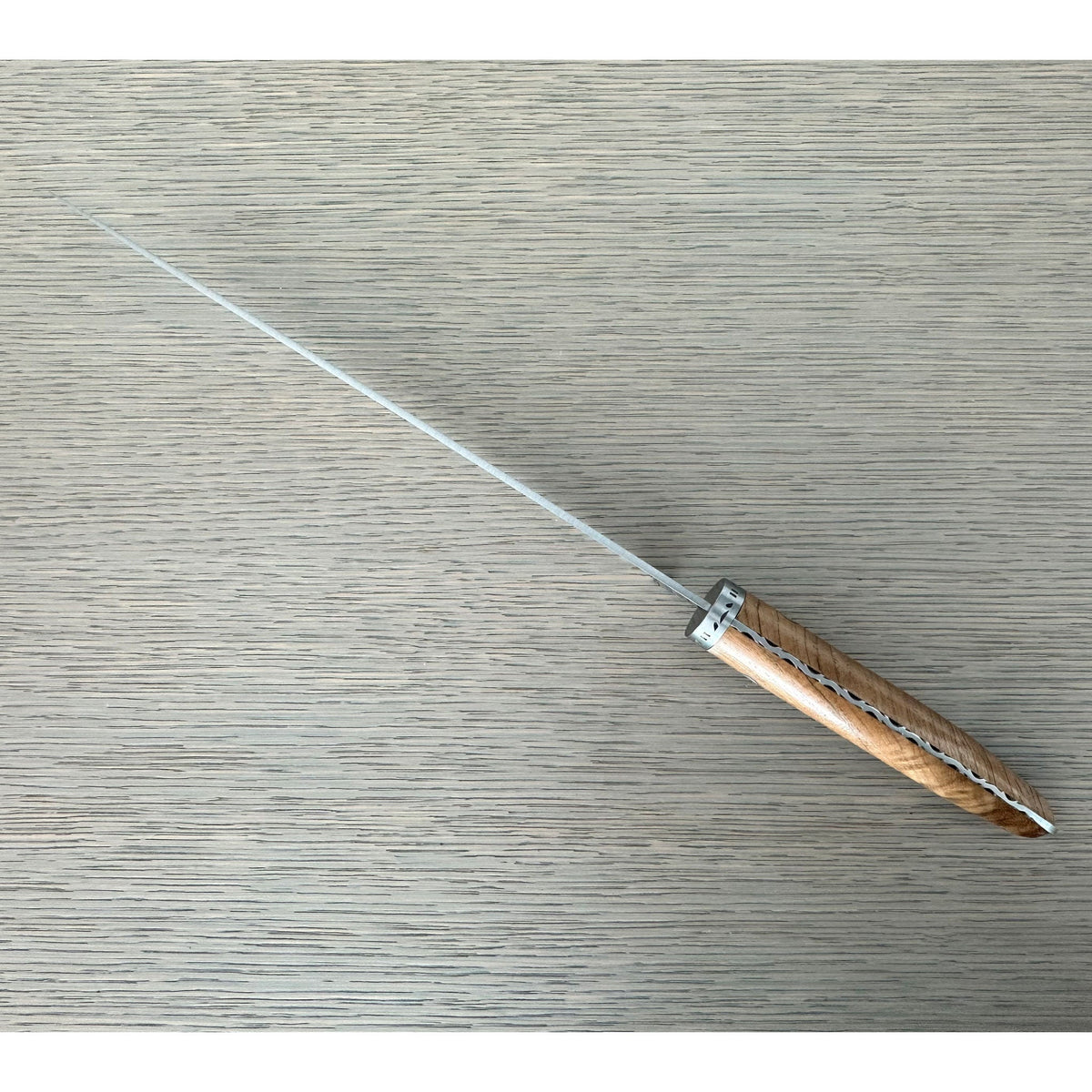 Bread knife lying diagonally on a pale surface