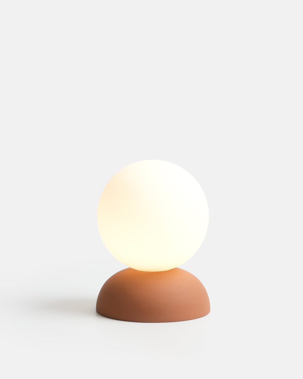 ceramic globe table lamp in Terracotta on a bedside shelf
