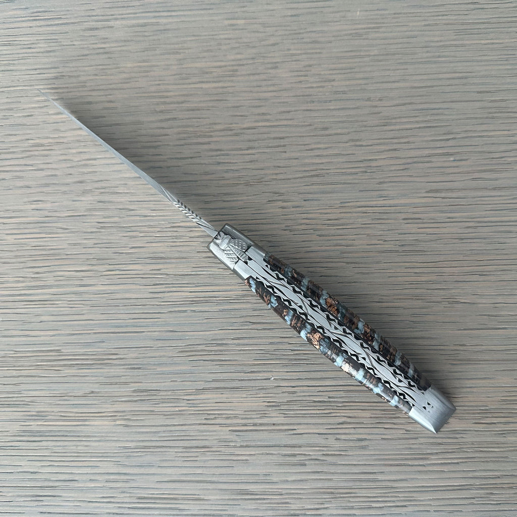 Open knife lying diagonally on pale wood