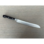 Bread knife lying with the serrated blade pointing down and right