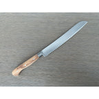 Bread knife lying with the serrated blade pointing up and right