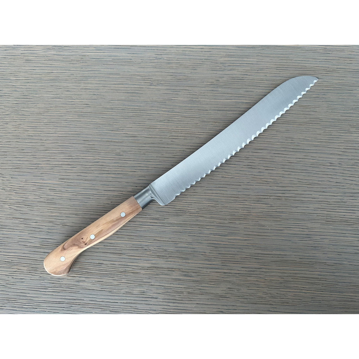 Bread knife lying with the serrated blade pointing up and right