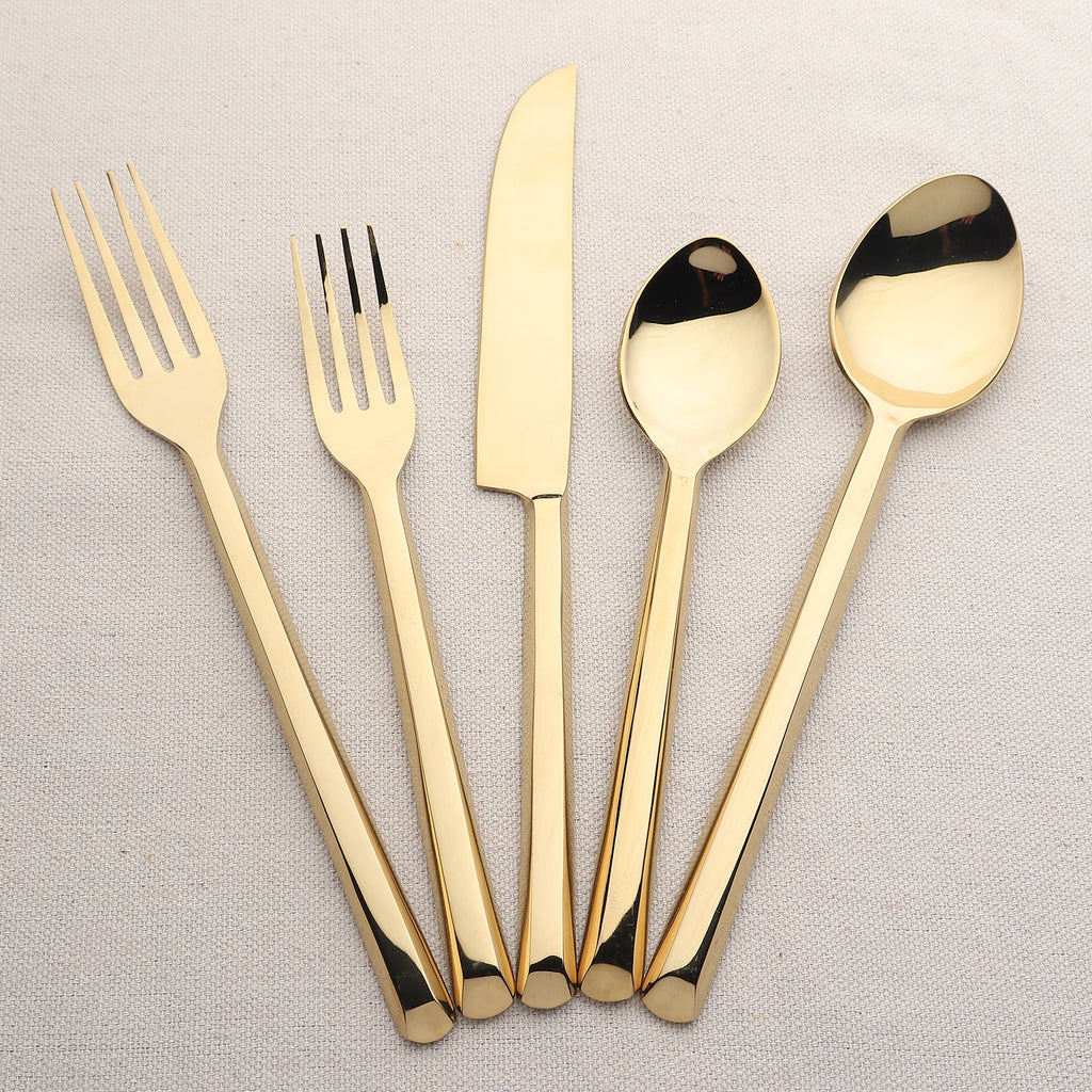 Set of gold cutlery including forks, knives, and spoons on a light gray background