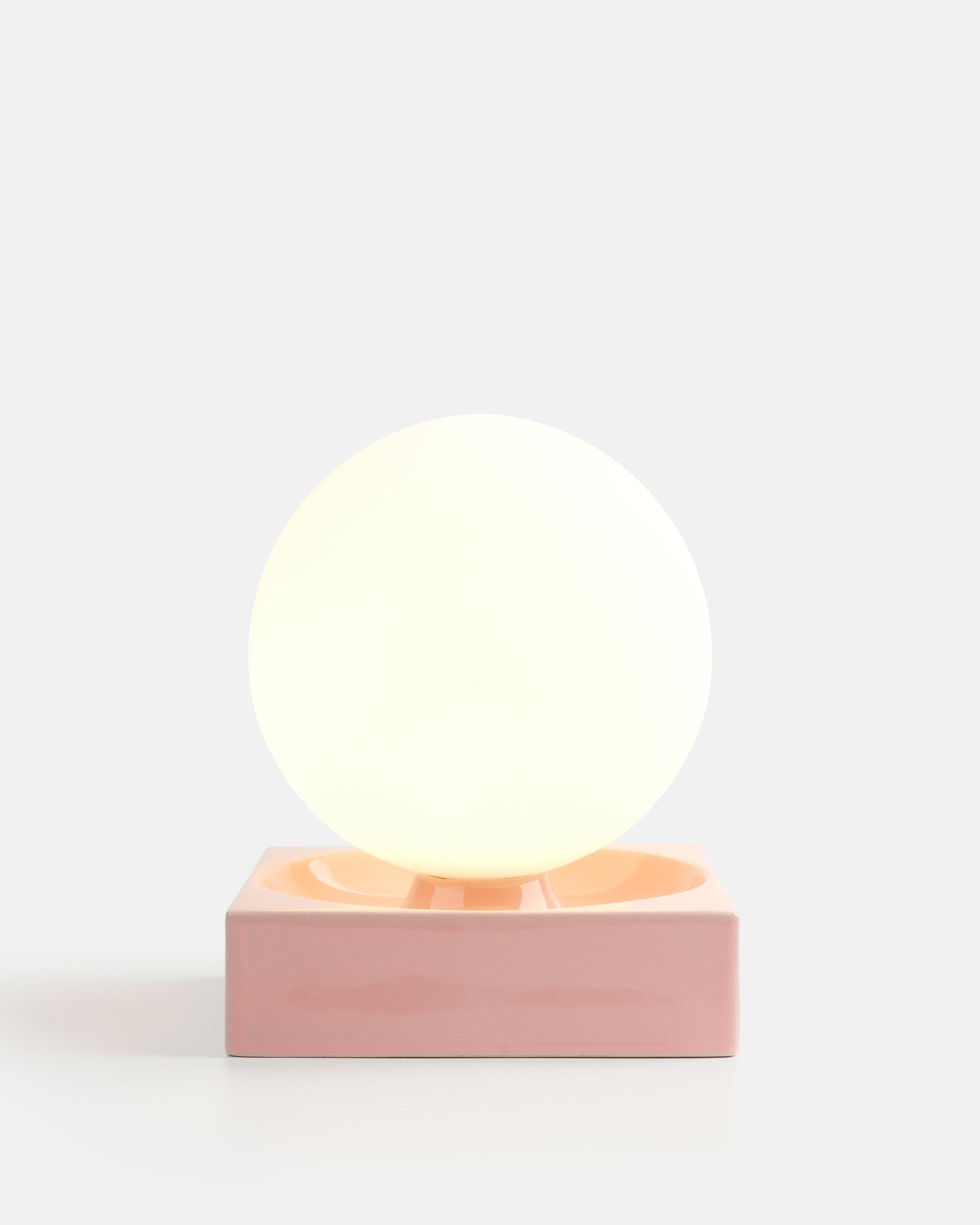 glossy ceramic globe lamp in Pink Glossy on a nightstand