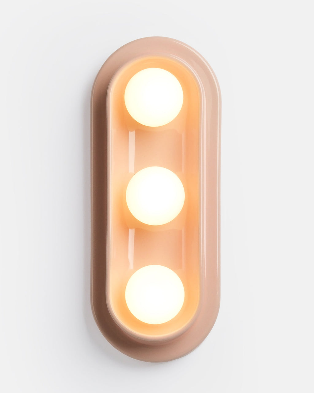 triple globe ceramic sconce in Pink Glossy beside a sofa