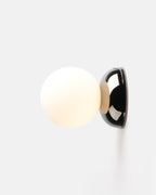 small chrome ripple sconce beside a bed