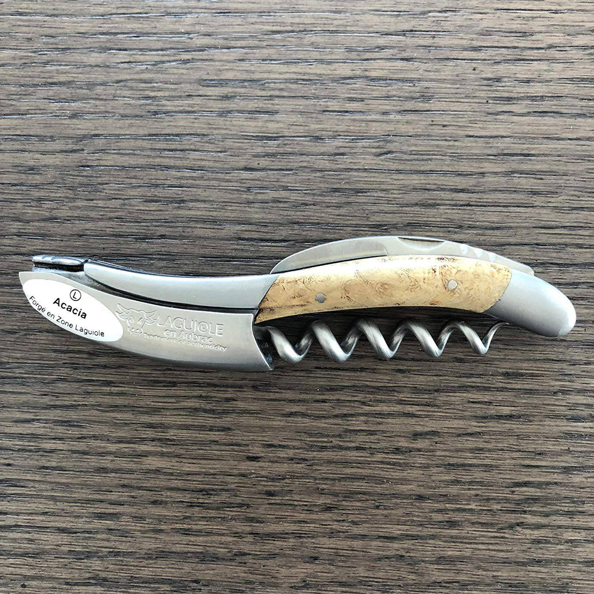 Folded acacia corkscrew lying on a dark wood table