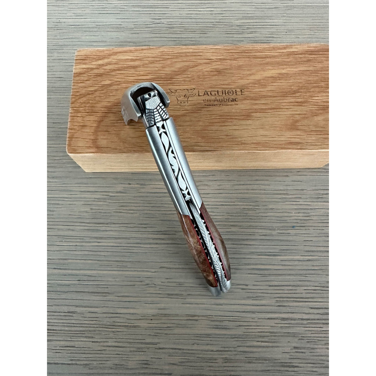 Folded corkscrew resting across the oak box