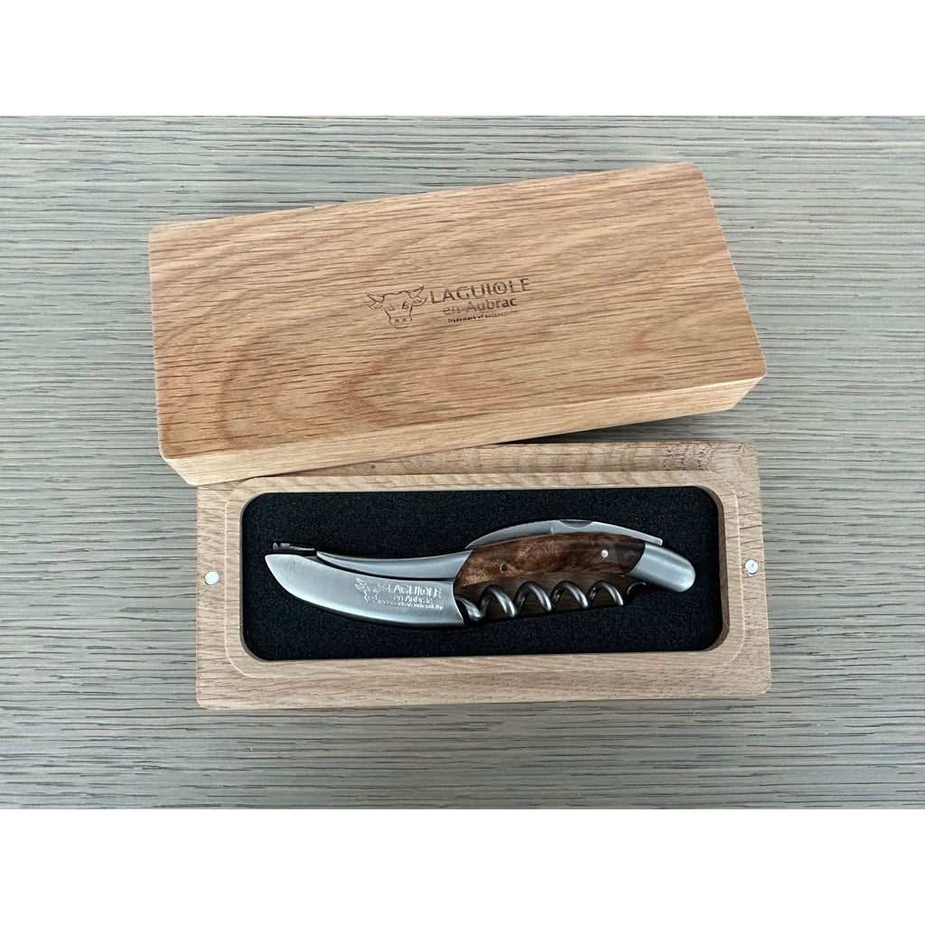 Corkscrew inside its open oak box on a grey surface