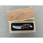 Corkscrew inside its open oak box on a grey surface
