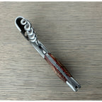 Folded corkscrew on a grey surface with the foil cutter end visible
