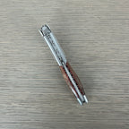 Folded grapevine corkscrew lying diagonally on a grey surface
