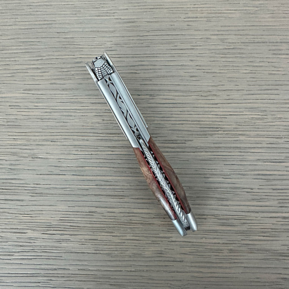 Folded grapevine corkscrew lying diagonally on a grey surface