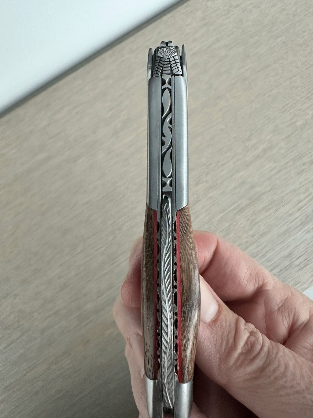 Hand holding the folded corkscrew to show the carved spine