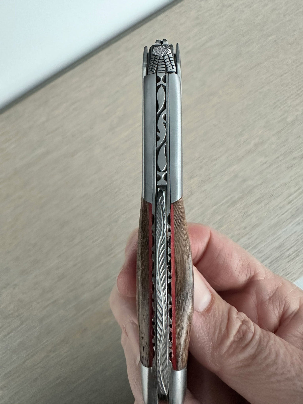 Hand holding the folded corkscrew to show the carved spine