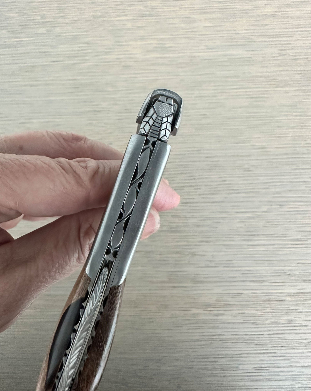 Hand holding the folded corkscrew to show the carved spine