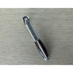 Folded ebony corkscrew lying diagonally on a grey surface
