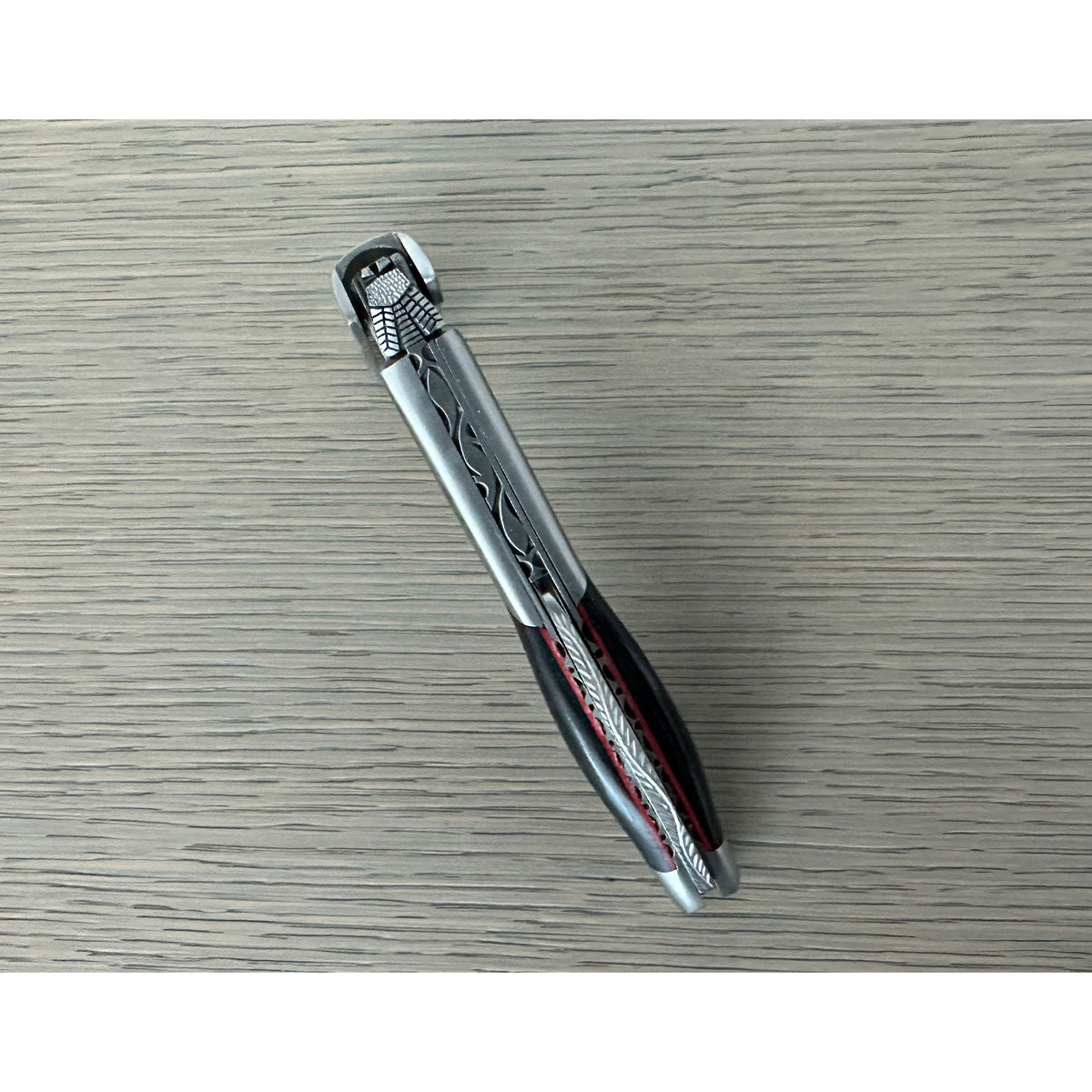 Folded ebony corkscrew lying diagonally on a grey surface