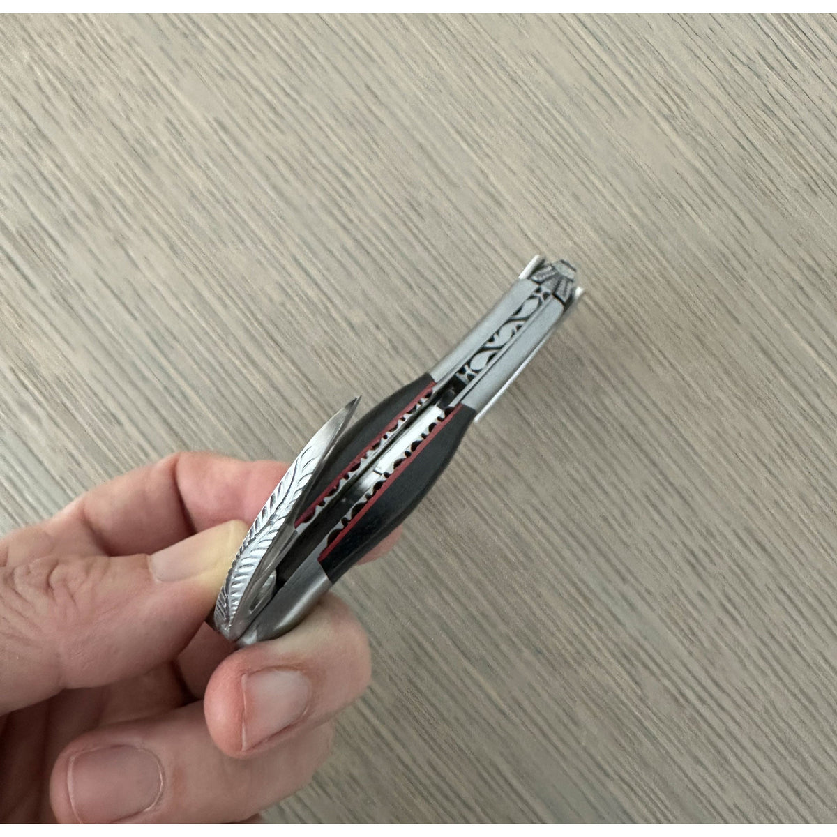 Hand opening the corkscrew to show the red lined spine